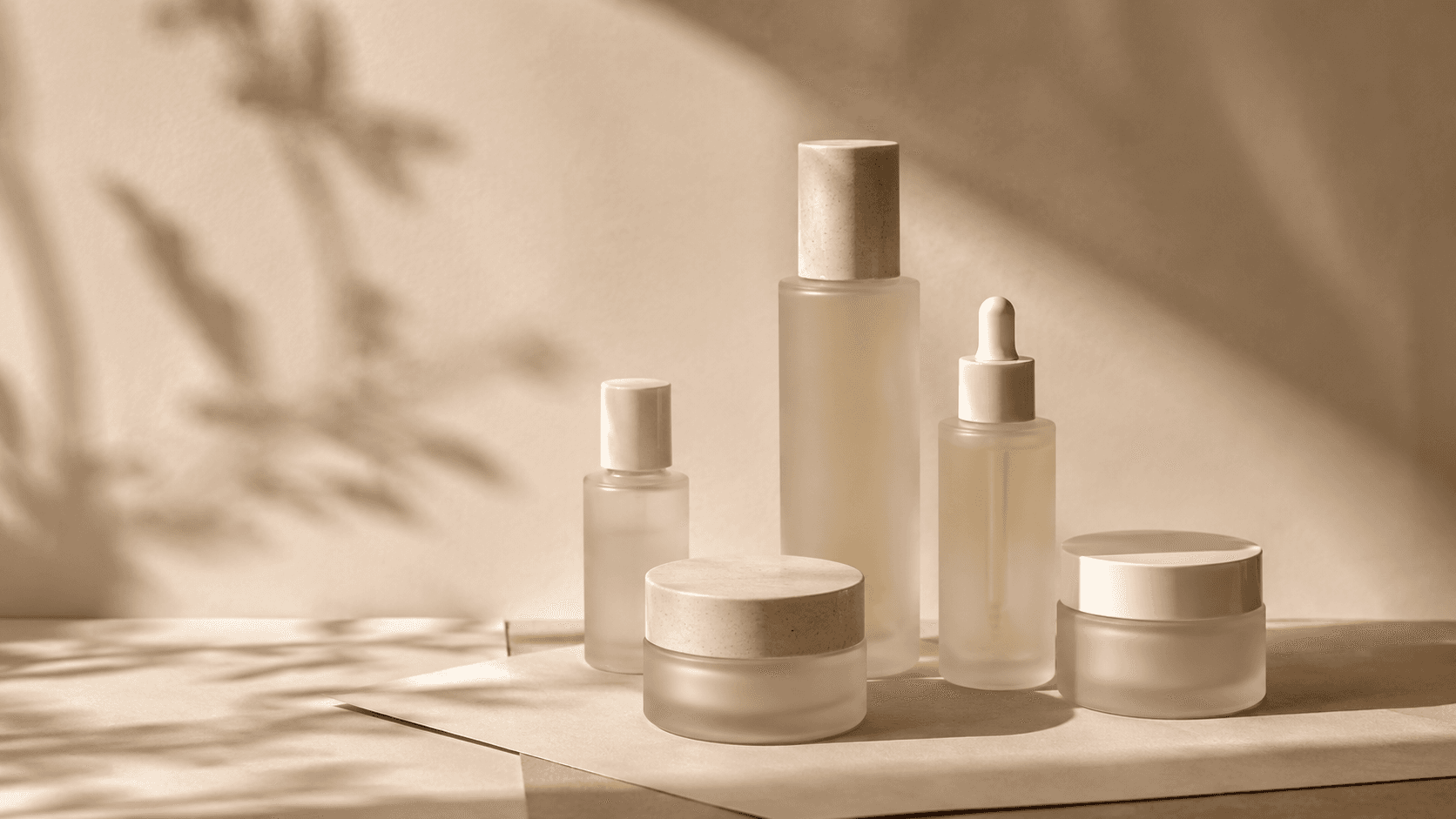 Bodegón editorial de productos de skincare sobre fondo cálido